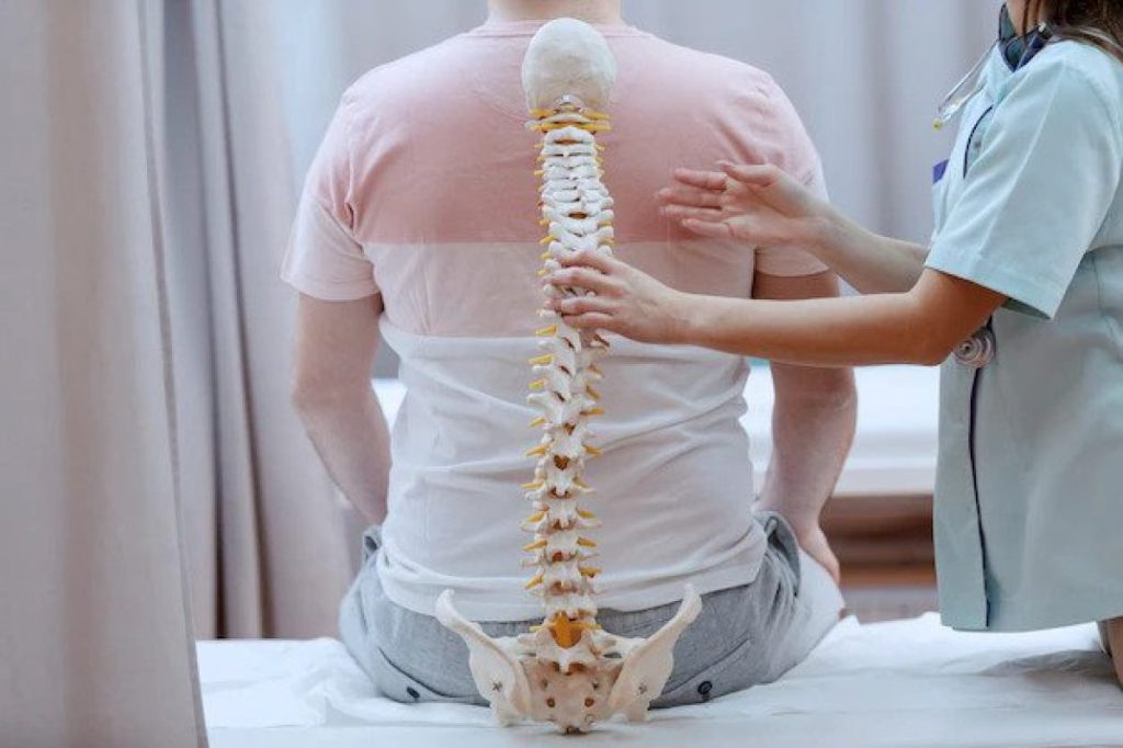 یک تصویر از ستون فقرات به همراه بیمار و یک پزشک طب فیزیکی